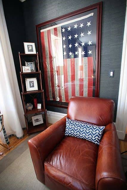 Framed American flag displayed behind a leather armchair with a decorative pillow.