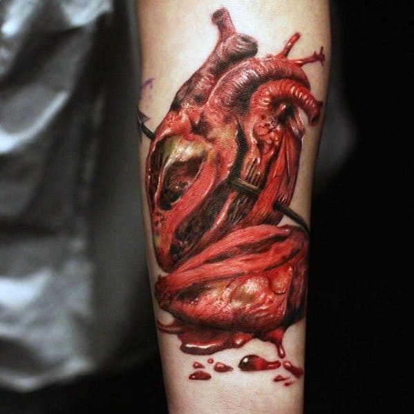 A realistic anatomical heart tattoo on a forearm, showing detailed veins and arteries in vibrant red and black ink