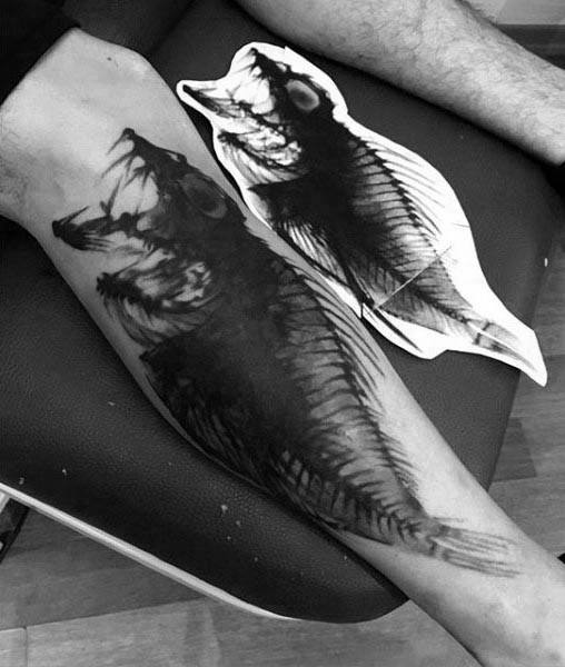 Black and grey leg tattoo of a fish skeleton in an abstract, brushstroke style, blending anatomical detail with artistic shading.