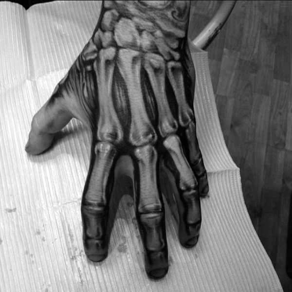 Black and grey hand tattoo of skeletal bones, designed with bold shadows to create a realistic, x-ray-style 3D illusion.