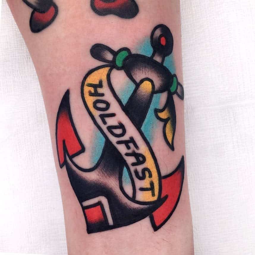 Tattoo of an anchor with a banner reading "HOLDFAST" and colorful details