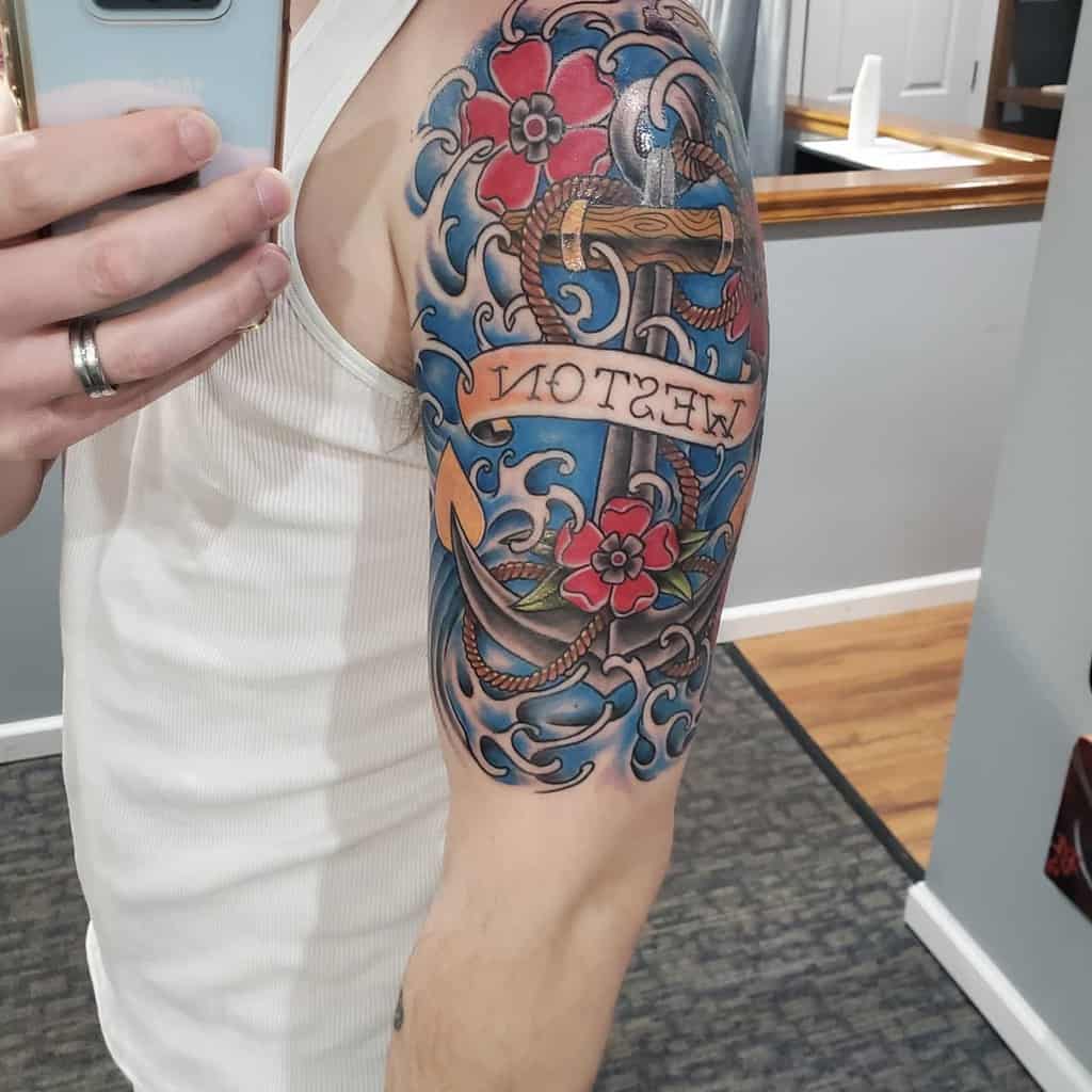 Colorful nautical-themed tattoo featuring an anchor, ocean waves, red flowers, and a banner with the name 'Weston'