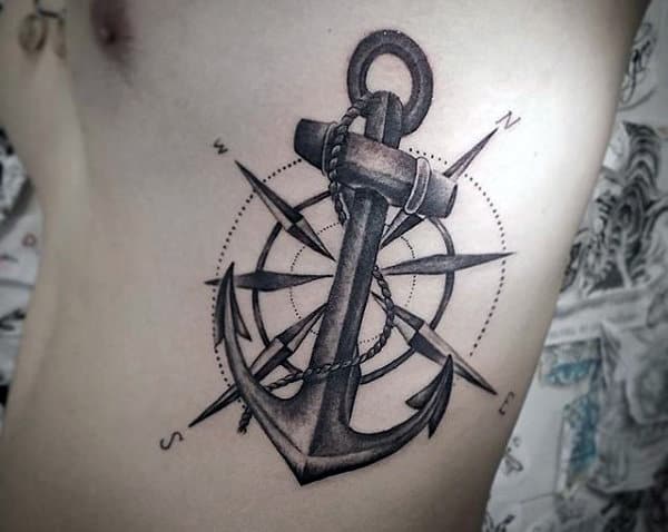 A tattoo of an anchor intertwined with a compass, complete with directional markers, elegantly graces the side of a person's torso