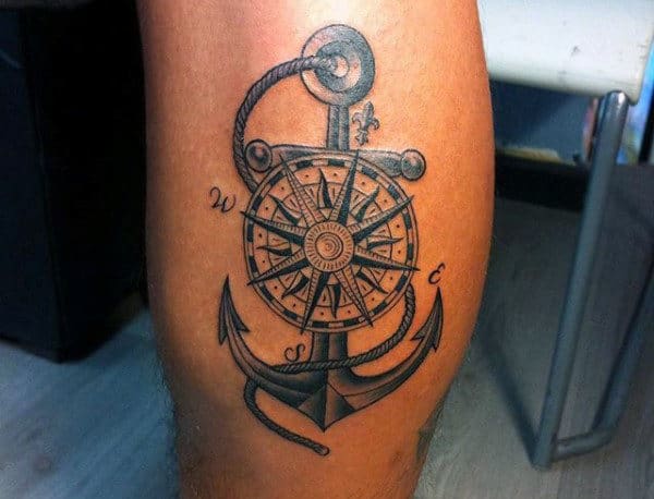 A tattoo of a nautical compass and anchor on a leg