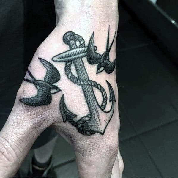 Tattoo of an anchor with two swallows on the back of a left hand
