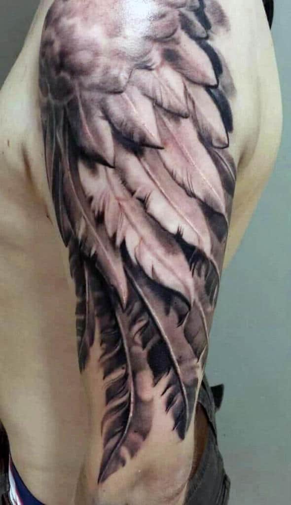 Close-up of a detailed feather tattoo on a person's shoulder and upper arm