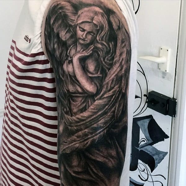 Tattoo of an angel on a person's upper arm showing folded hands and large wings