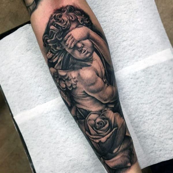 Tattoo of an angel covering its face with a large rose on forearm