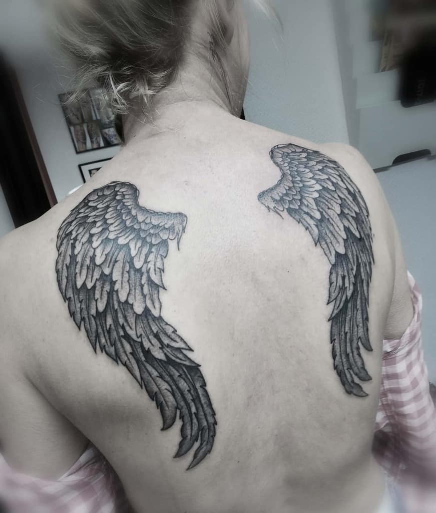 A large black and grey angel wing tattoos with intricate shadings