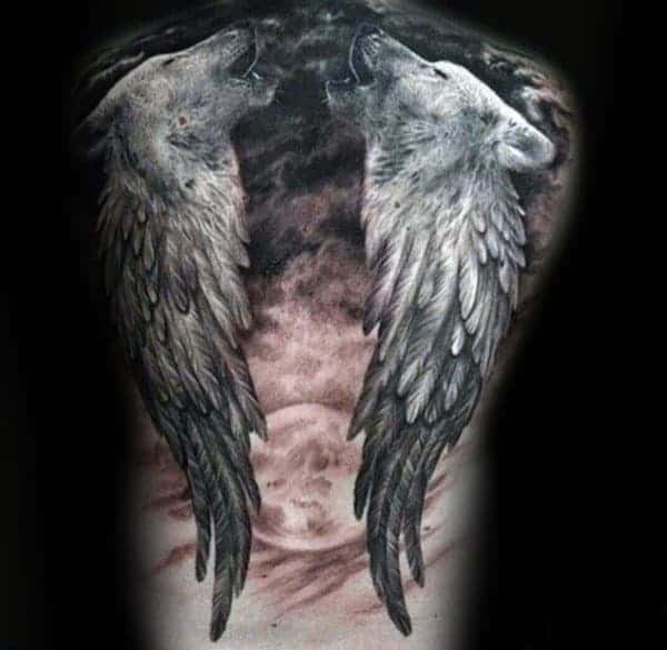 Tattoo of two wolves howling with feathered wings, set against a dark, cloudy background