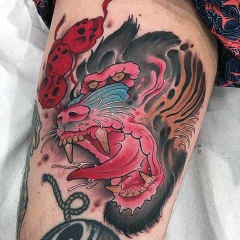Neo-traditional baboon tattoo with bold colors, fierce expression, and dynamic shading, featuring intense red and blue tones for a striking look.