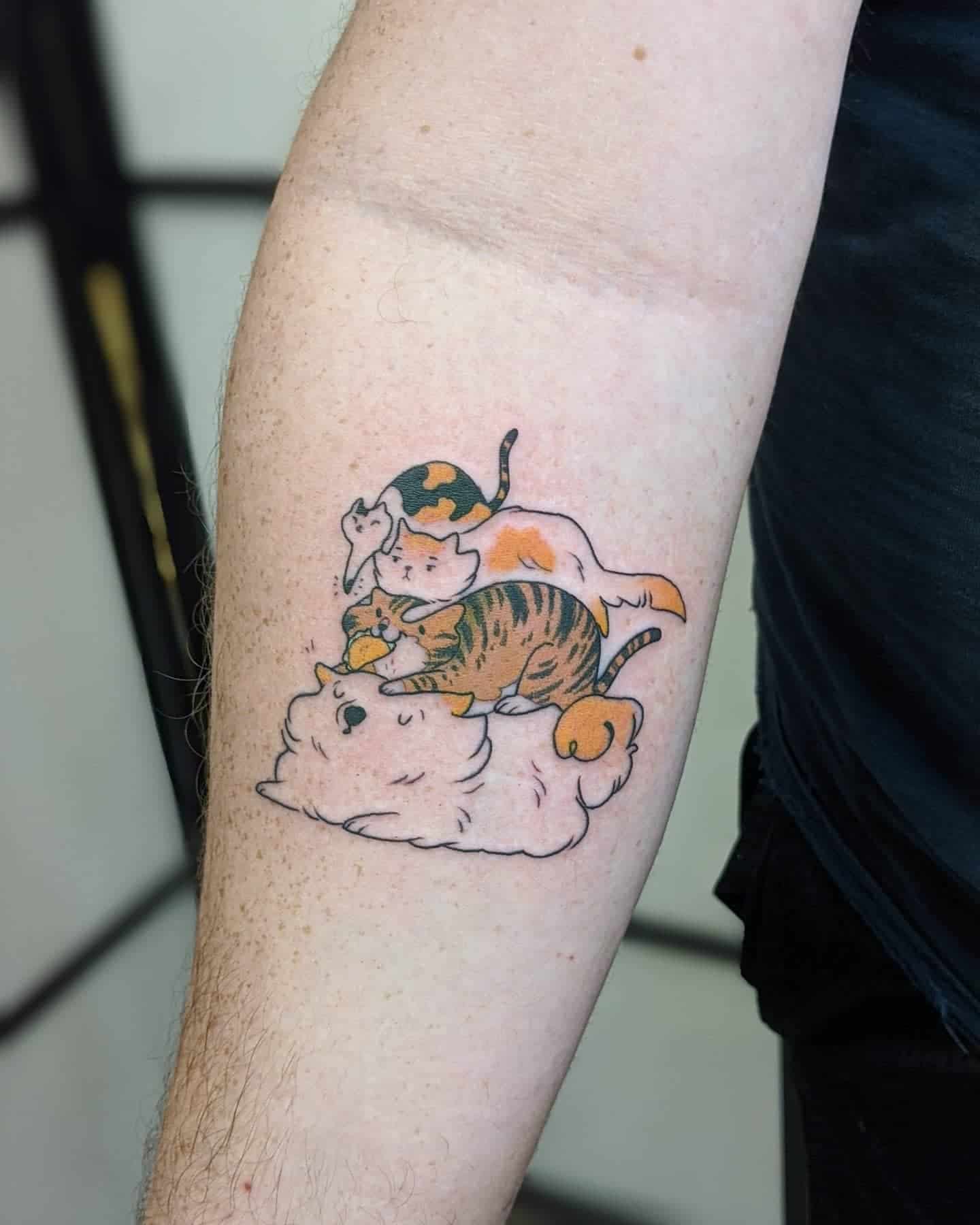 Charming tattoo of four playful cats in a pile, with a mix of calico and tabby patterns, the orange cat biting a taco