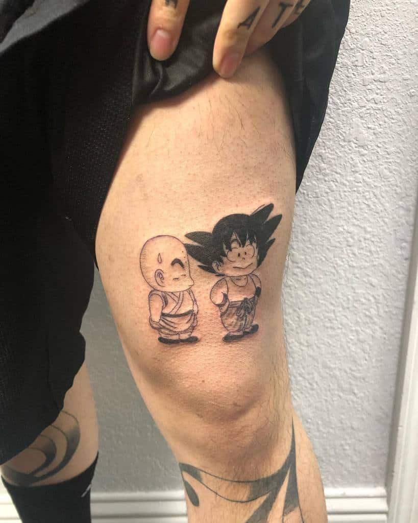 A tattoo of young Goku and Krillin from Dragon Ball, both in their classic outfits, standing side by side in black and white.