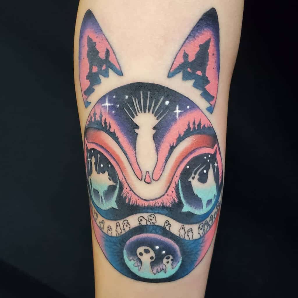 Vibrant tattoo of a stylized wolf's face with kodama spirits, featuring a galaxy-like color gradient and nature-inspired elements in the design.