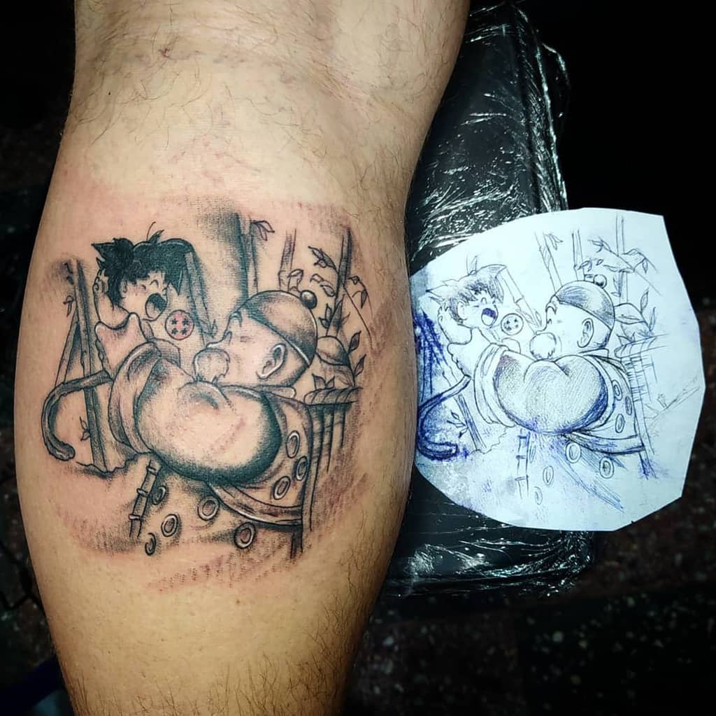 A black-and-grey tattoo depicting a scene from *Dragon Ball* with Goku being held by Master Roshi, a memorable moment from the series, shown alongside the initial sketch for reference.