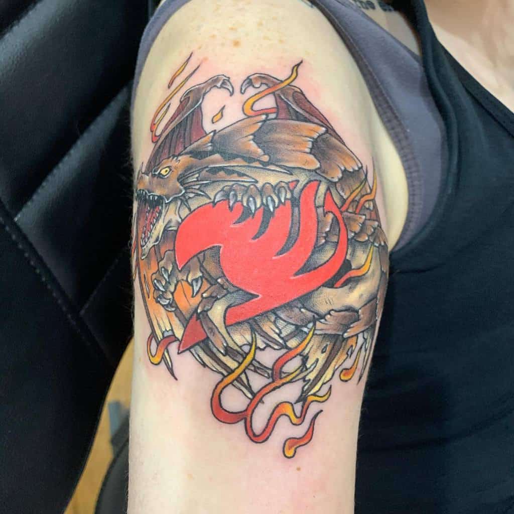Vibrant tattoo of the Fairy Tail guild emblem with a fierce dragon wrapping around it, featuring fiery colors, bold shading, and dynamic details.