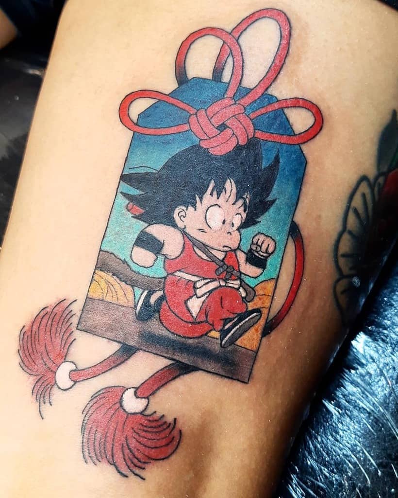 A tattoo of young Goku from Dragon Ball running, with a money bag design featuring a knot and broomstick-like tassels.