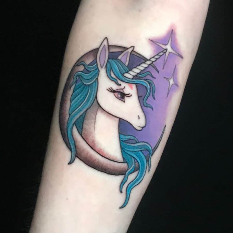 Colorful unicorn tattoo with a flowing blue mane, set against a crescent moon and a purple starry background for a mystical, dreamy effect.