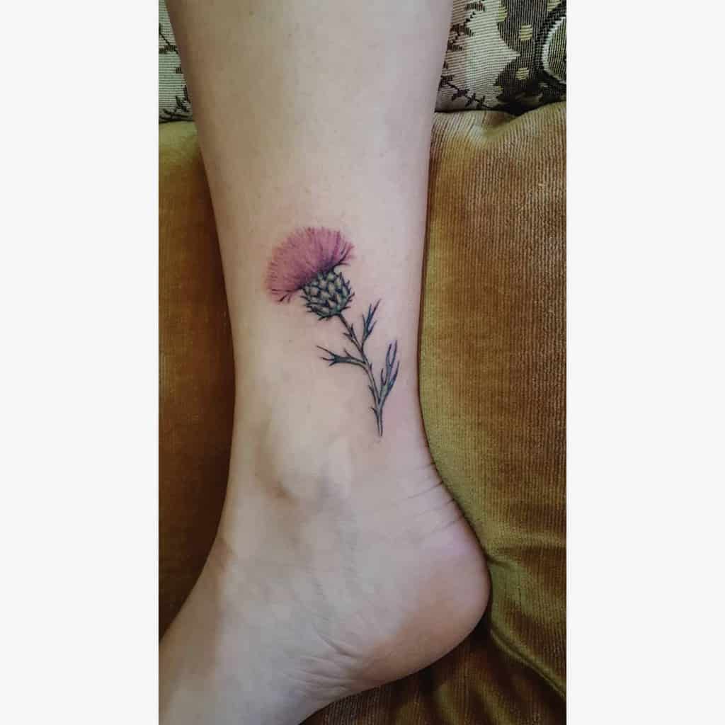A delicate tattoo of a thistle flower on the ankle, capturing its intricate beauty