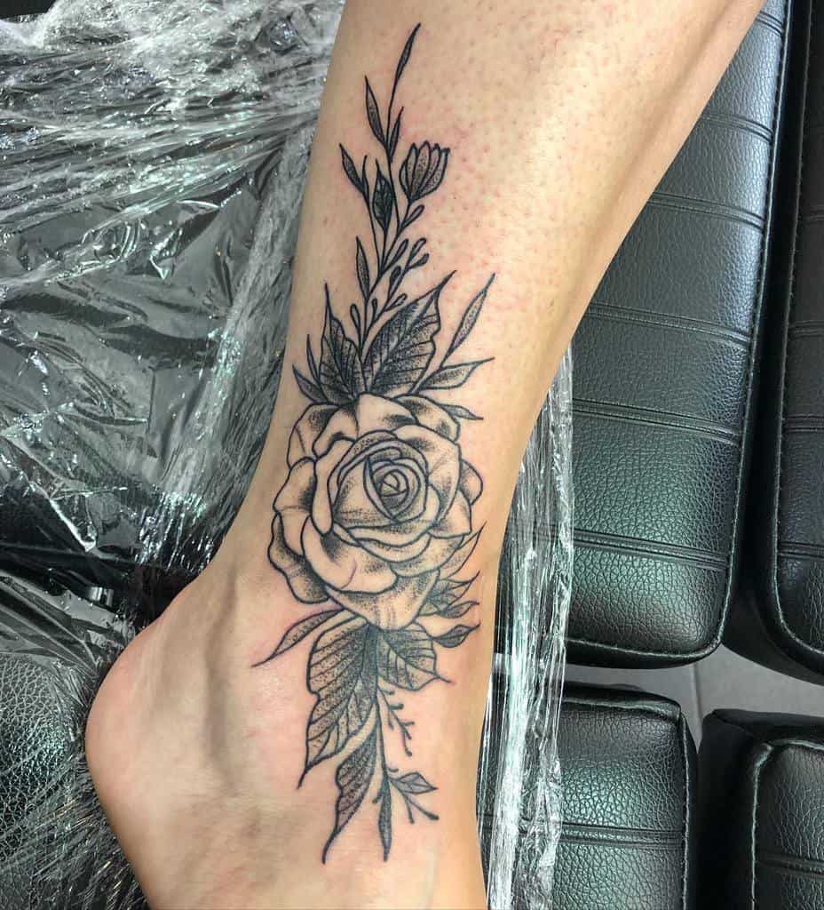 Black rose and leaves tattoo on an ankle