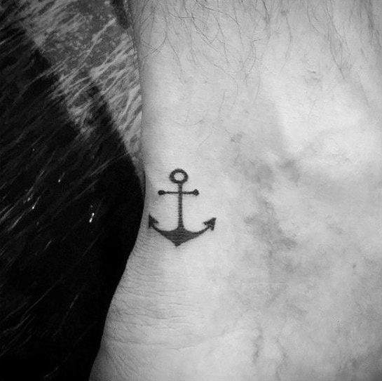 Small and simple anchor tattoo on the ankle, featuring a minimalist black design that symbolizes stability, grounding, and a nautical spirit.