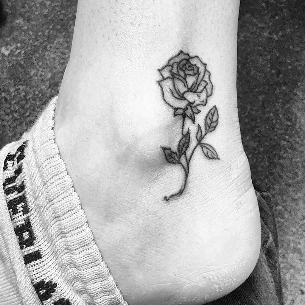 Black and white tattoo of a rose on an ankle