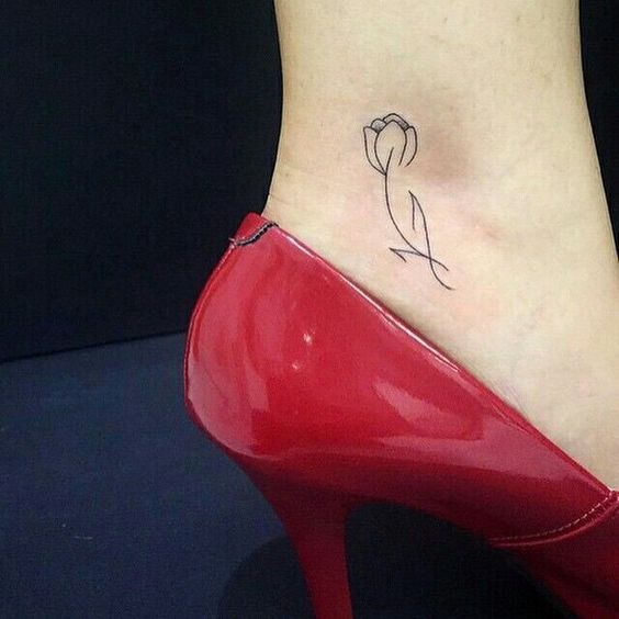 A minimalist black-line tulip tattoo on the ankle, featuring a delicate curved stem and simple petals for an elegant look.