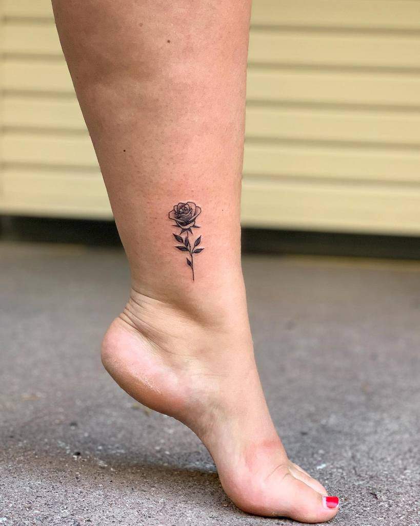 Ankle with a small, black rose tattoo on the side