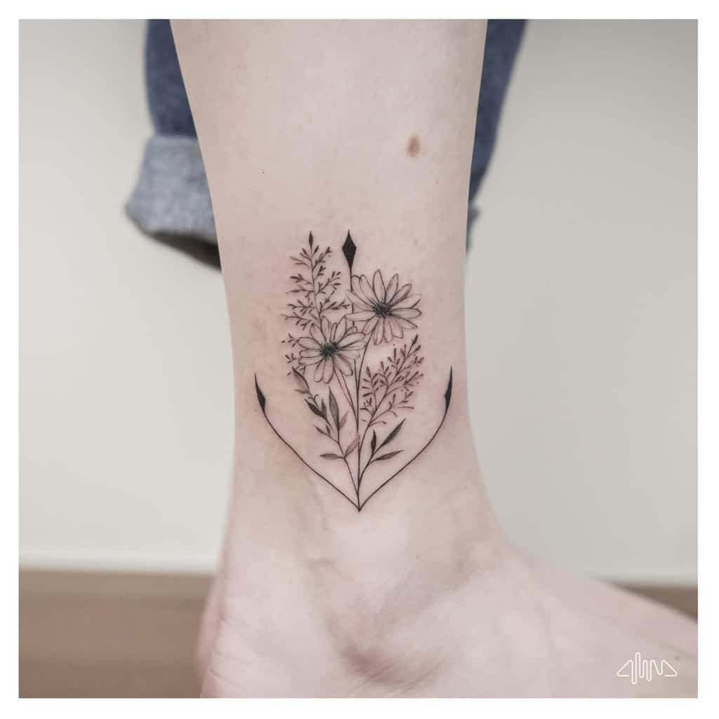 Minimalist floral tattoo on ankle with anchor design