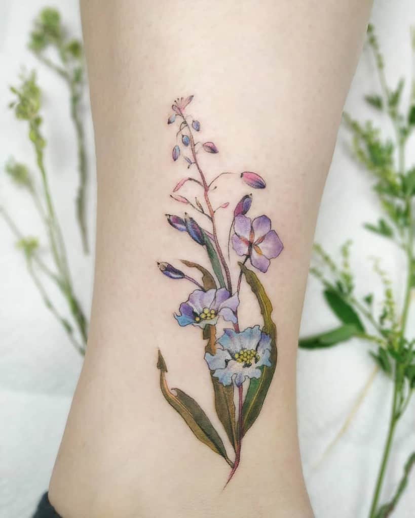 Delicate floral tattoo with purple and pink flowers on an ankle
