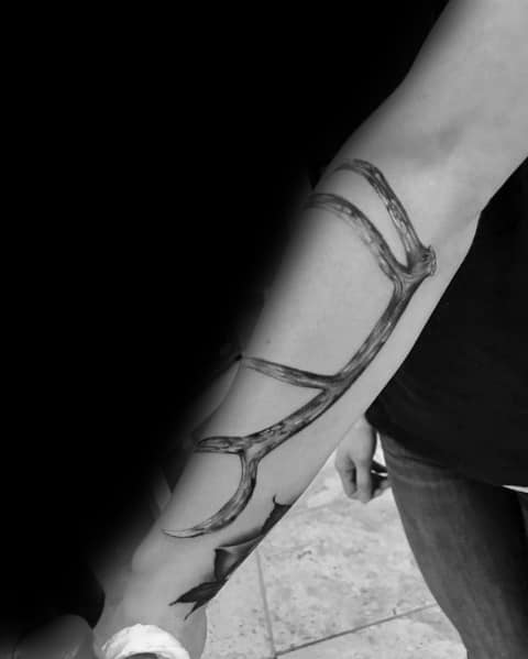 Black and grey elk antler tattoo wrapping around a man's forearm, featuring realistic shading and fine details for a bold, natural look.