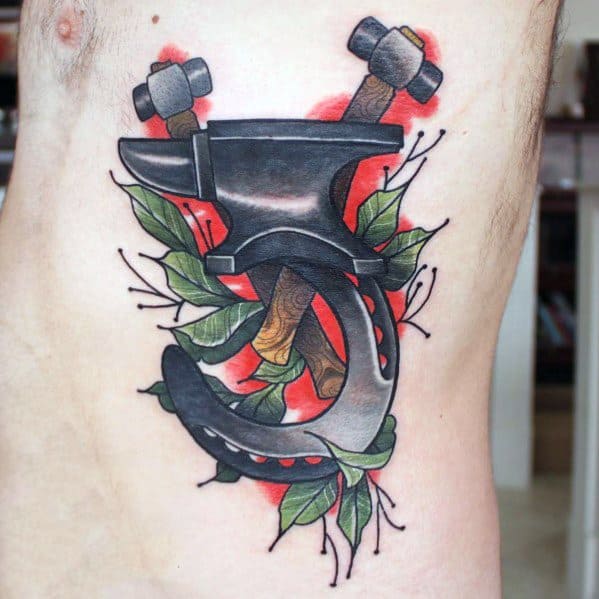 Large anvil tattoo on the side of the torso with two hammers, green leaves, and a red background for a bold, vibrant look.