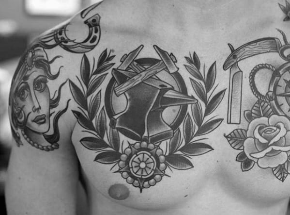 Black and grey chest tattoo featuring an anvil, crossed hammers, laurel wreath, and flower centerpiece in a bold traditional style.