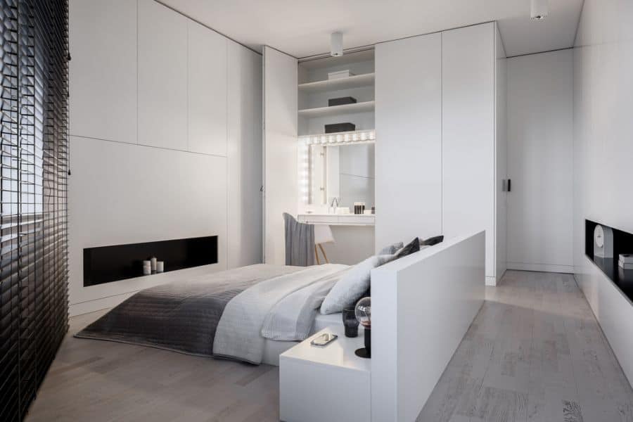 Modern minimalist bedroom with white walls, grey bedding, and built-in vanity.