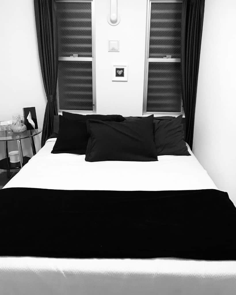 Black and white bedroom with black pillows, blanket, and minimalist decor.
