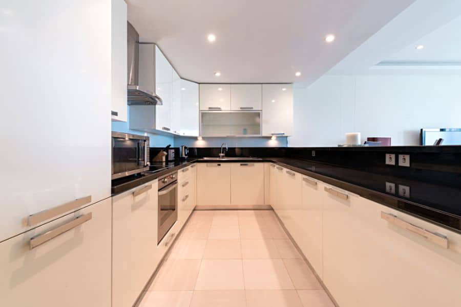 Spacious modern kitchen with white cabinets, black countertops, and built-in appliances.