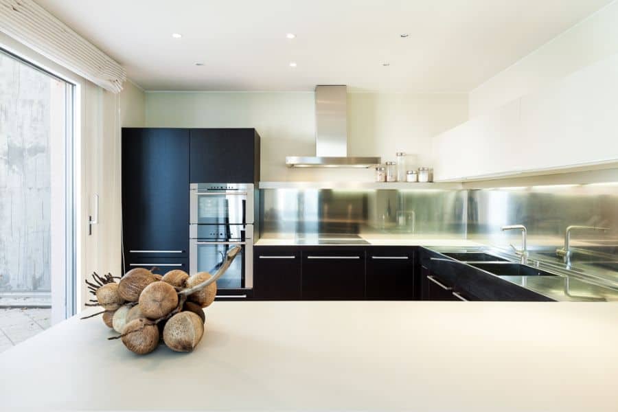 Modern kitchen with black cabinets, stainless steel backsplash, and white countertop island.