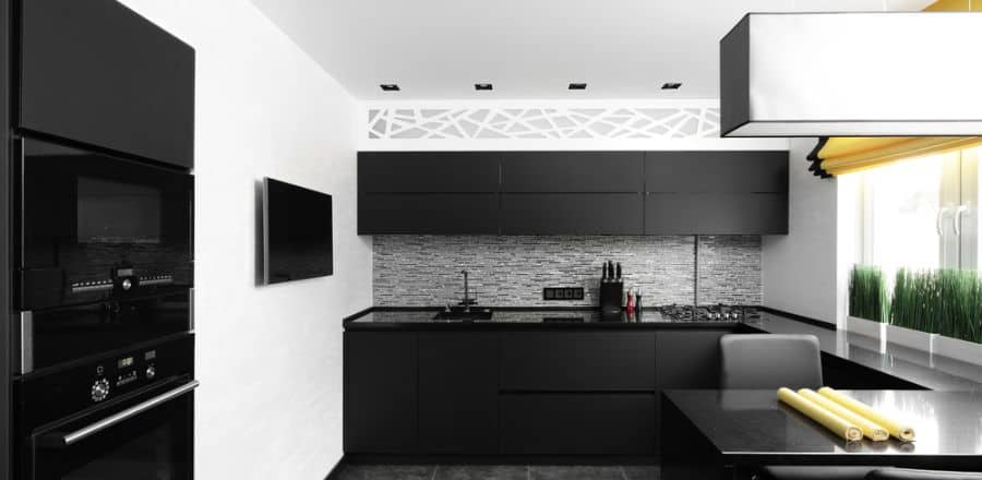 Modern kitchen with black cabinets, mosaic backsplash, built-in appliances, and yellow accents.