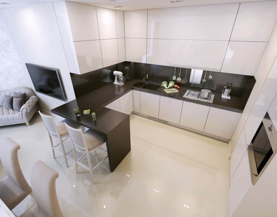 Modern U-shaped kitchen with white cabinets, black countertops, and bar seating area.