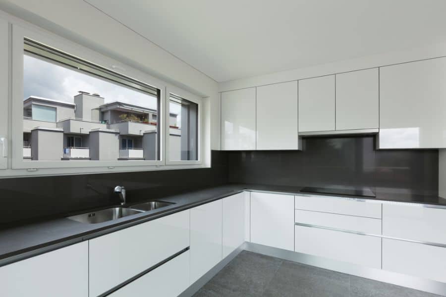 Minimalist kitchen with white cabinets, black countertops, and double sink.x