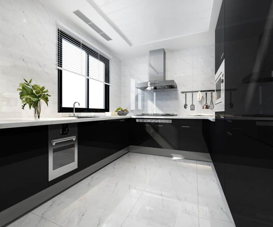 Modern kitchen with black cabinets, white marble floors, and stainless steel appliances.