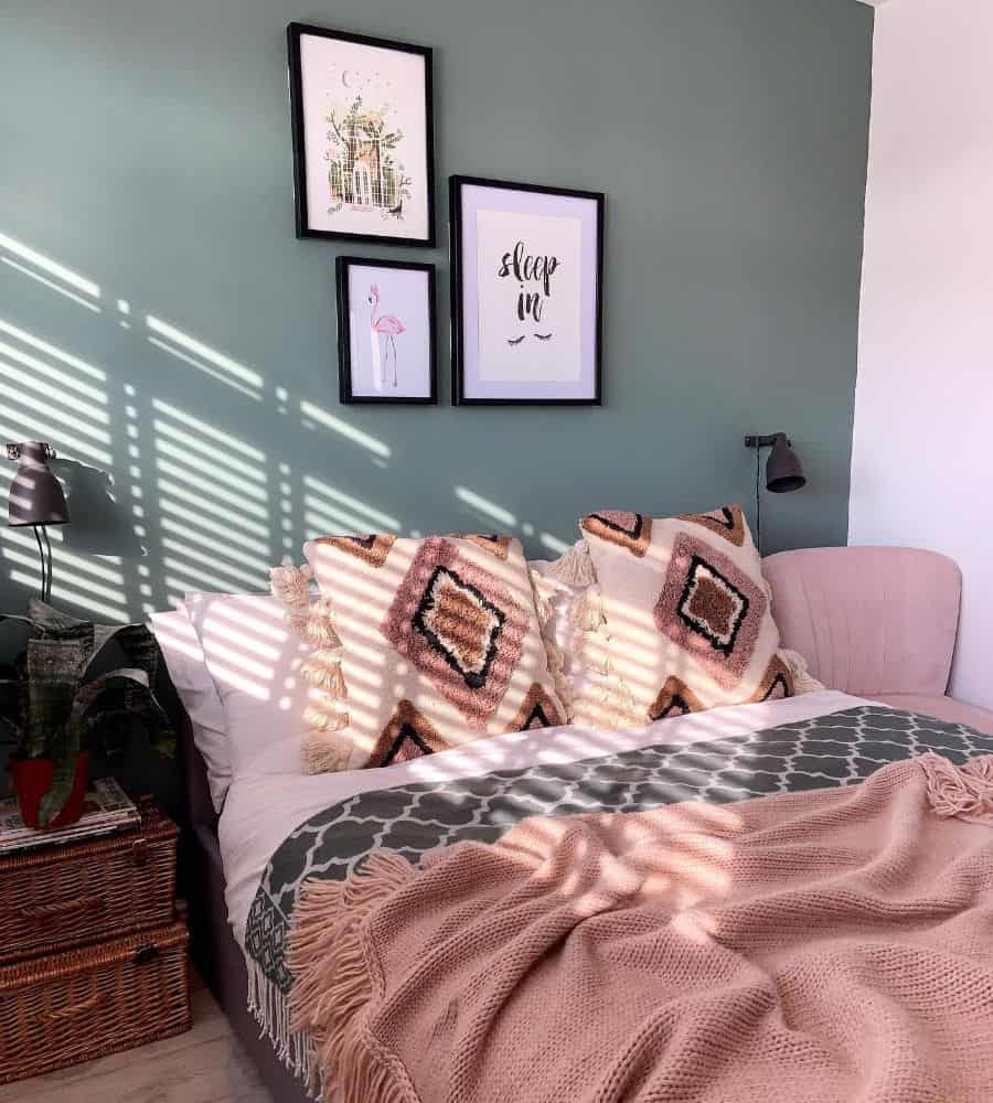 Small bedroom with green accent wall, framed art, and patterned pillows on cozy bedding.