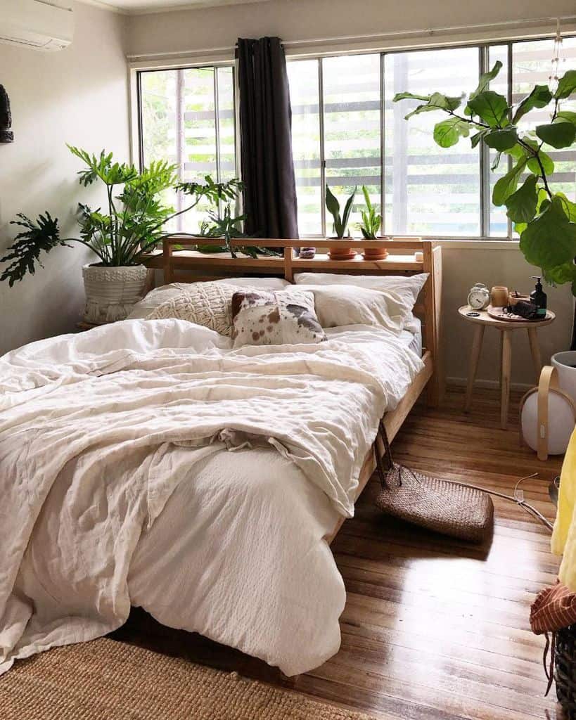 Small bedroom with lush indoor plants, cozy bedding, and hardwood floors.