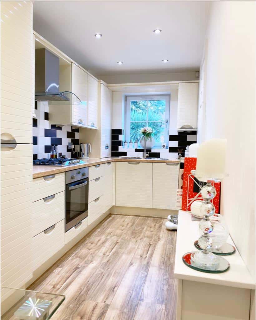 apartment galley kitchen white cabinets white and black tile splashback recessed ceiling lights