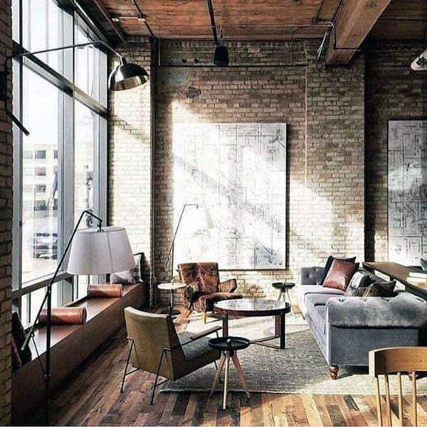 Industrial living room with brick walls, large windows, modern furniture, and natural light.