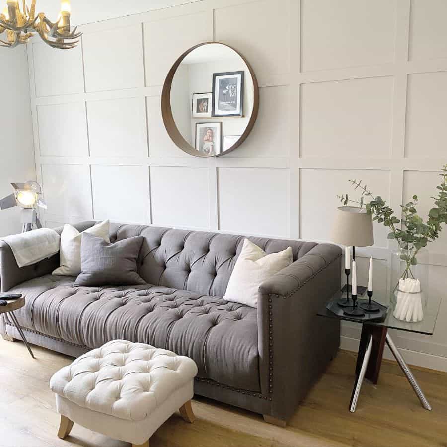 Stylish living room with a gray tufted sofa, round mirror, and minimalist decor