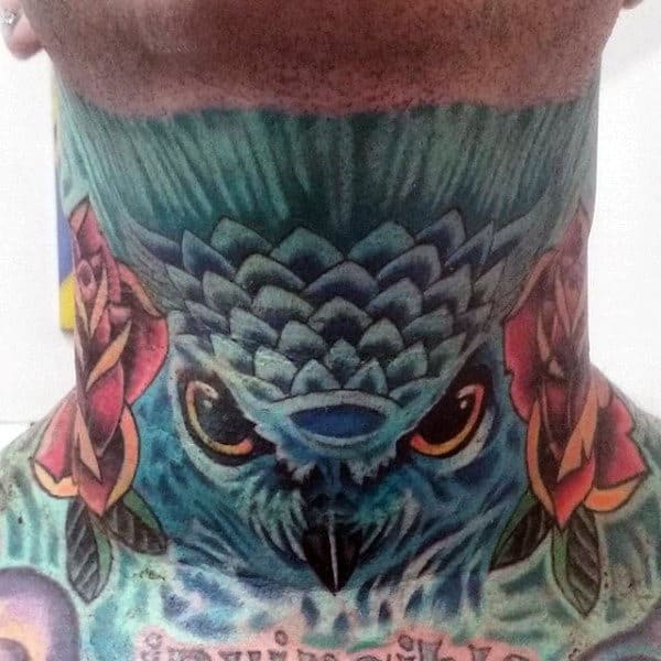 Vibrant throat tattoo of a blue owl with piercing eyes, intricate feather details, and bold roses on the sides for a striking look