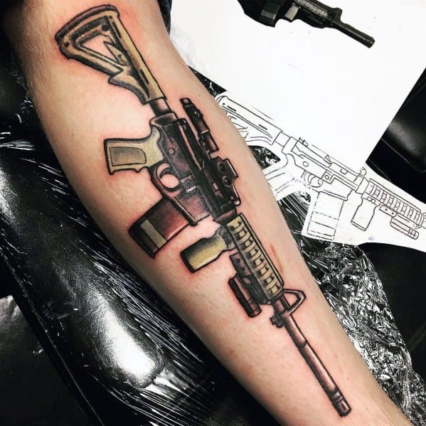 Colorful AR-15 tattoo on the forearm, featuring bold outlines and shading with tan and black details, symbolizing strength, precision, and firearm appreciation.