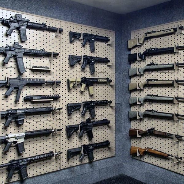 Gun room with pegboard walls displaying an array of rifles and firearms neatly organized.