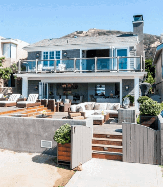 Modern beach house with multiple patios, a spacious deck, and mountain backdrop